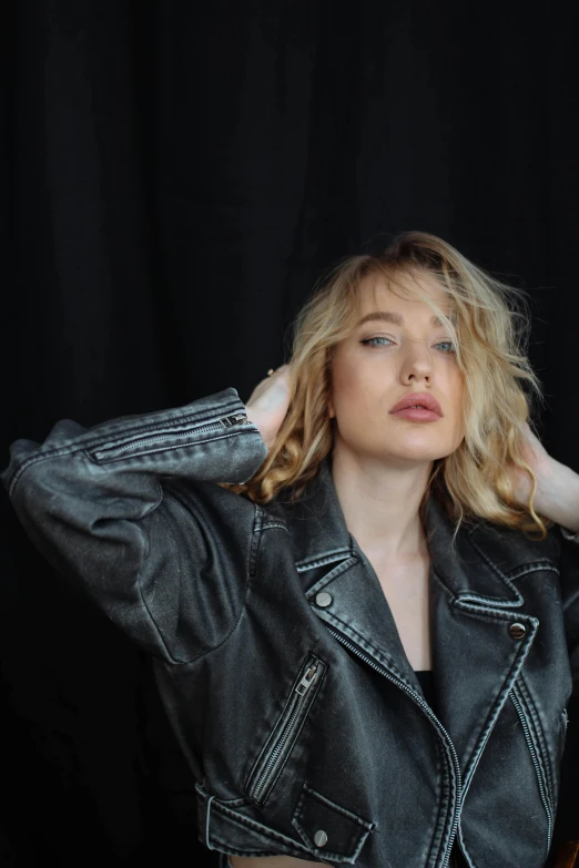 a woman in a leather jacket, is posing