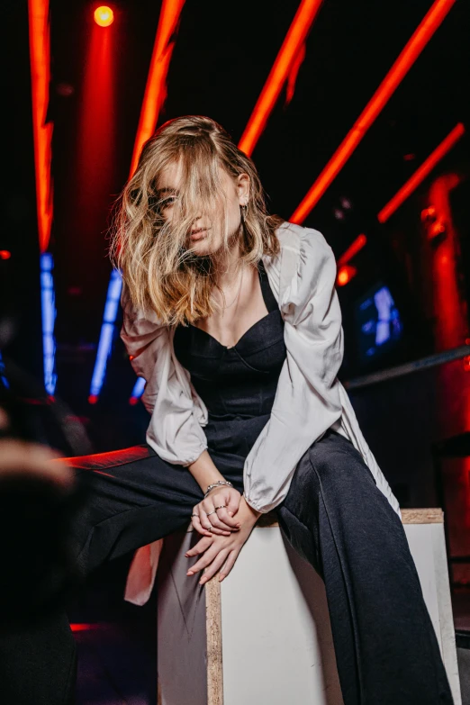 a blonde girl sitting on top of a chair in front of neon lights