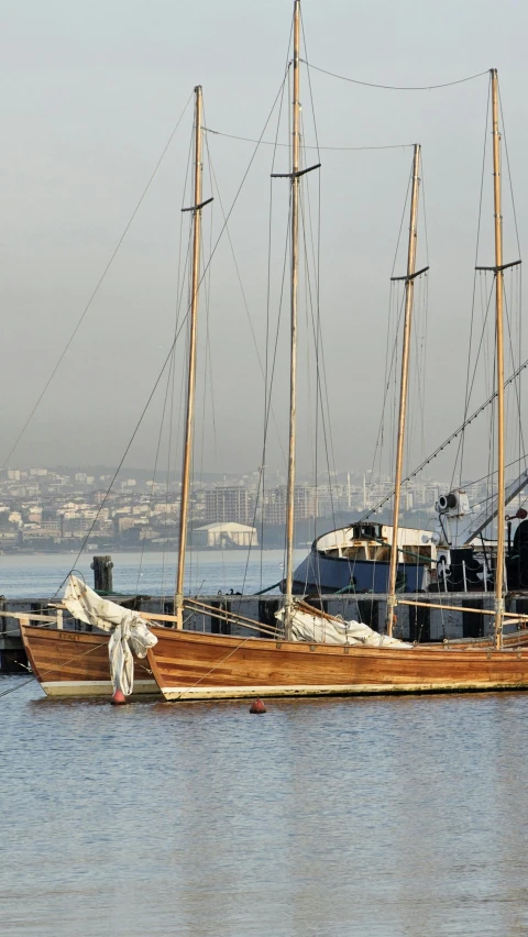 two large masted sail boats moored at a dock