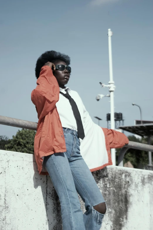 black woman standing on side of cement wall with cellphone up to her ear