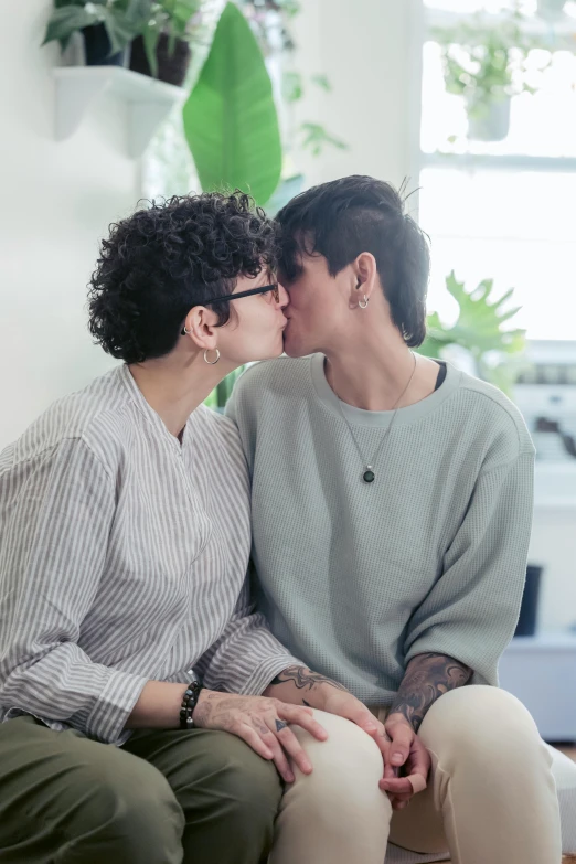 a young man kisses the nose of a woman in an apartment