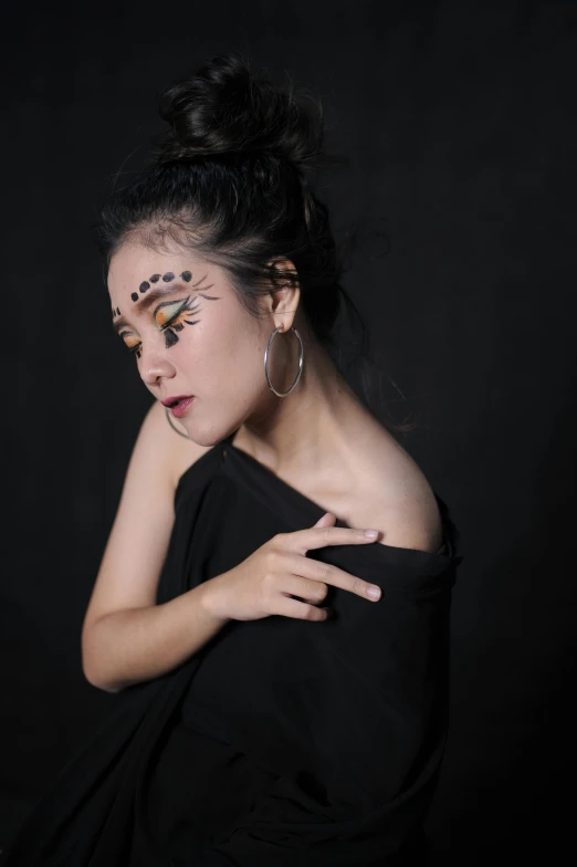 a woman is posing in a black dress with face paint