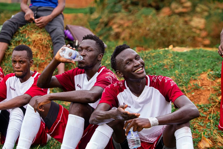 a group of people sitting on the ground drinking bottles