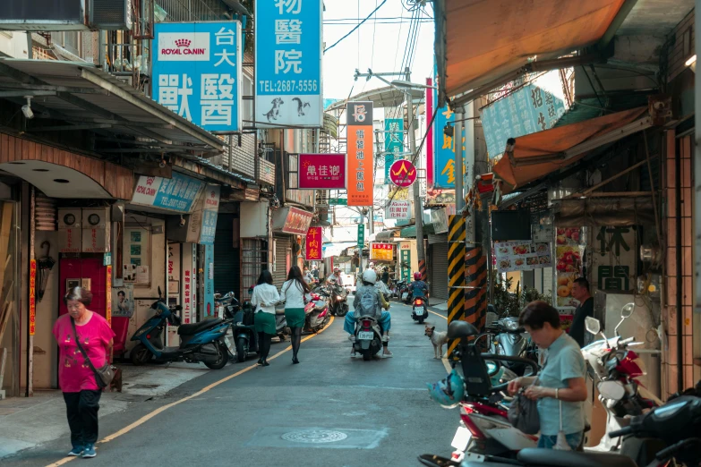 a man walks on a narrow street with signs hanging from buildings