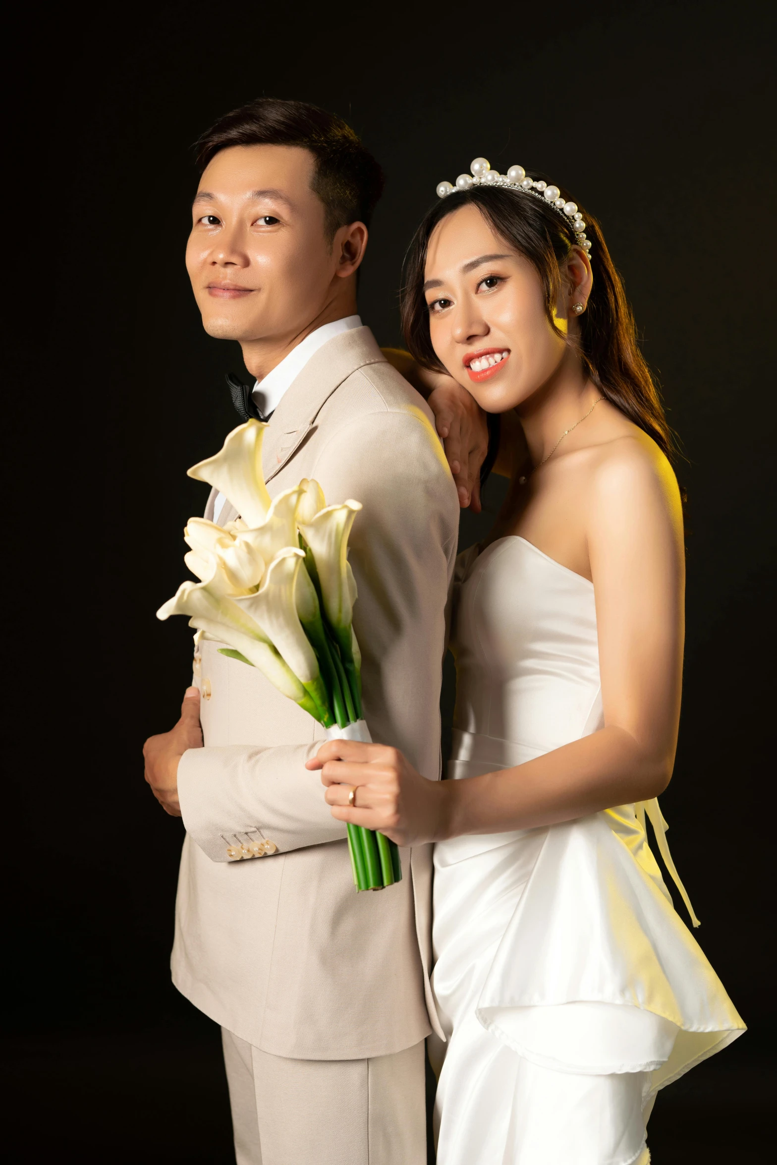 young bride and groom pose for po with flowers