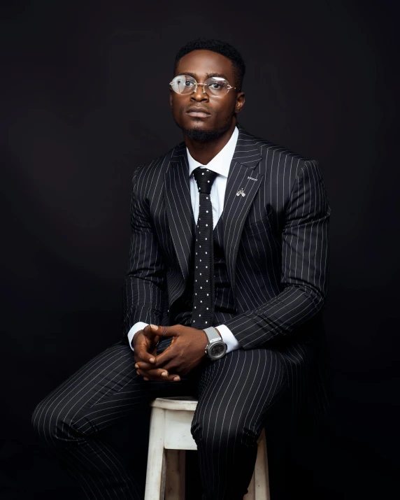 a man in glasses sitting on a stool