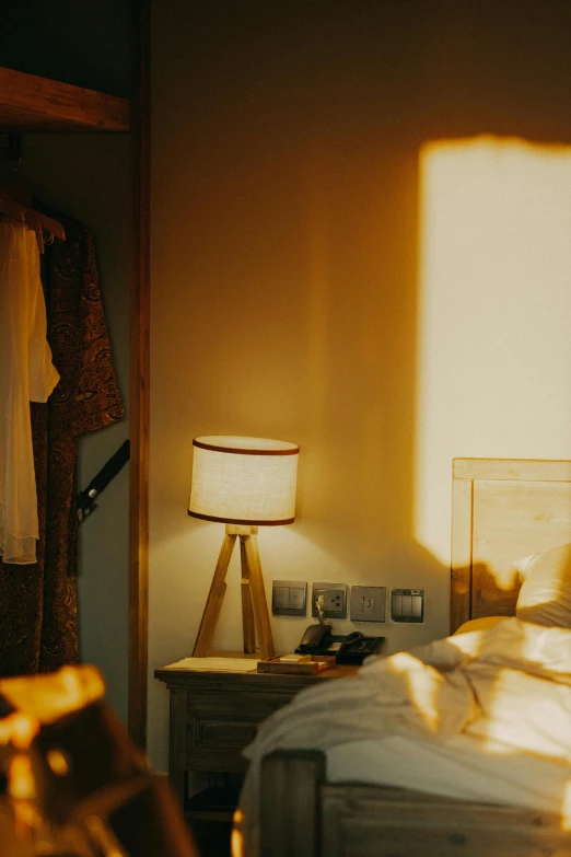 sun shines through the room onto a white bed and a small table