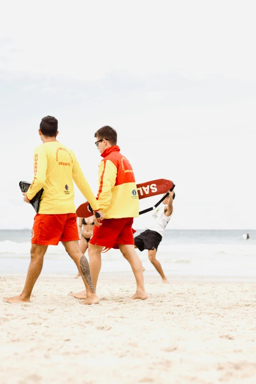 two guys carrying surfboards on a beach