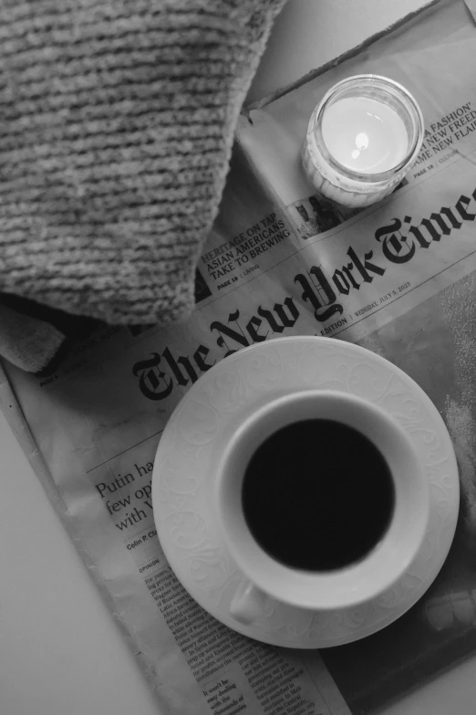 a cup of coffee sitting on top of a newspaper