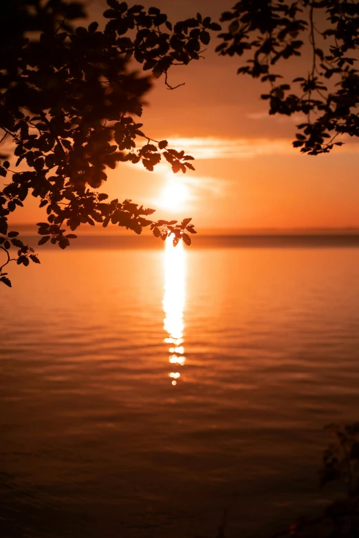 the sun is setting over a calm body of water