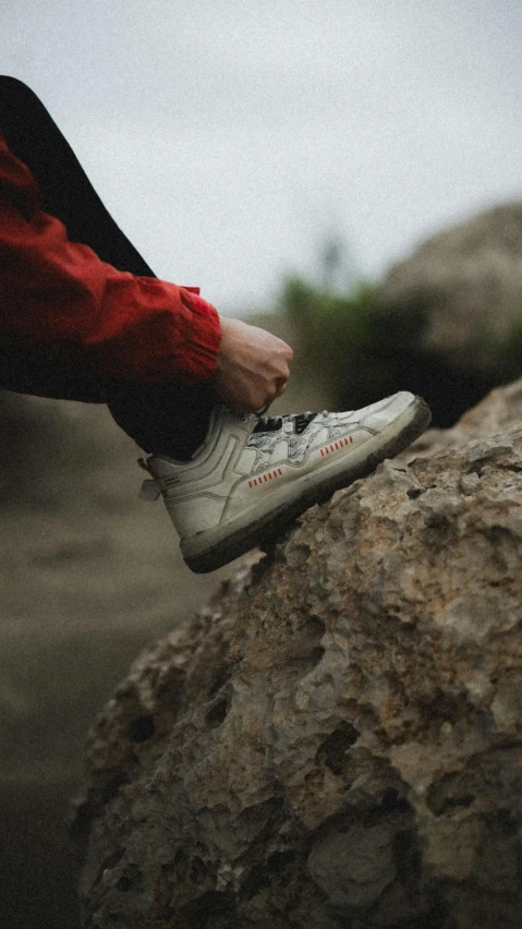 the man is sitting on the rock with his shoes on