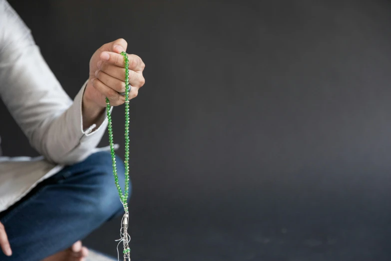 a person sitting down with a green beaded necklace on their ankle