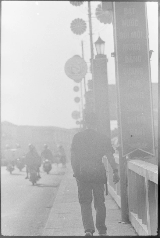 a man walks down the sidewalk past a lamppost