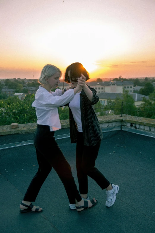 two women stand together outside at sunset