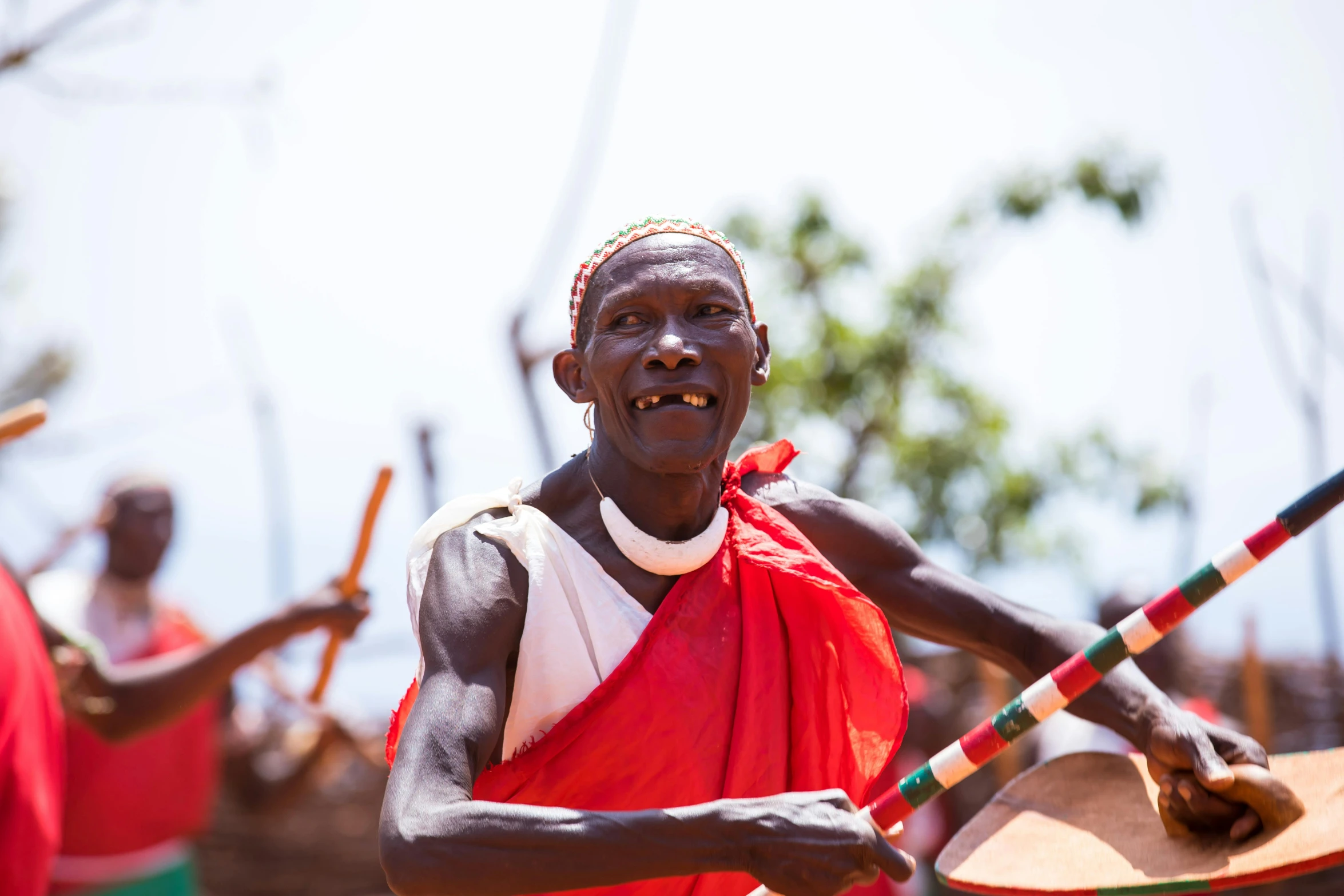 two african dancers in red outfits and a drummer