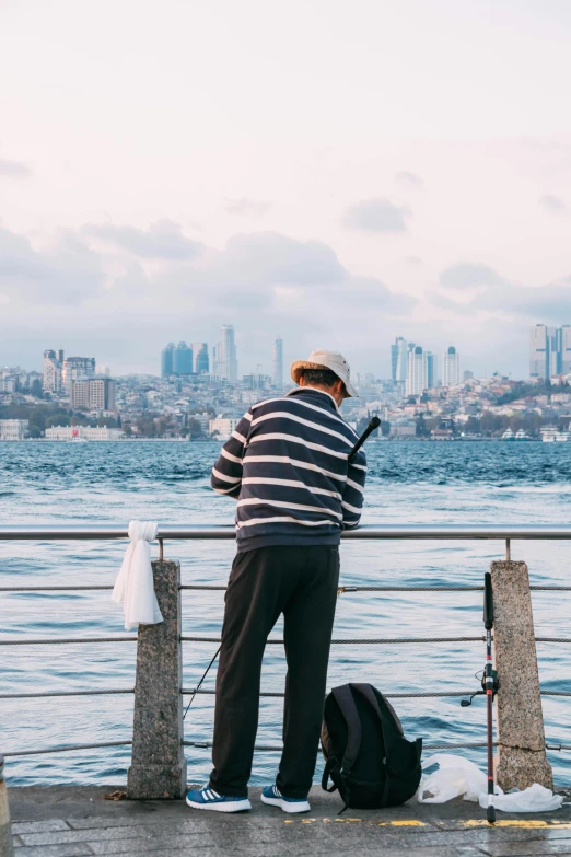 an old man standing by the water with his surfboard