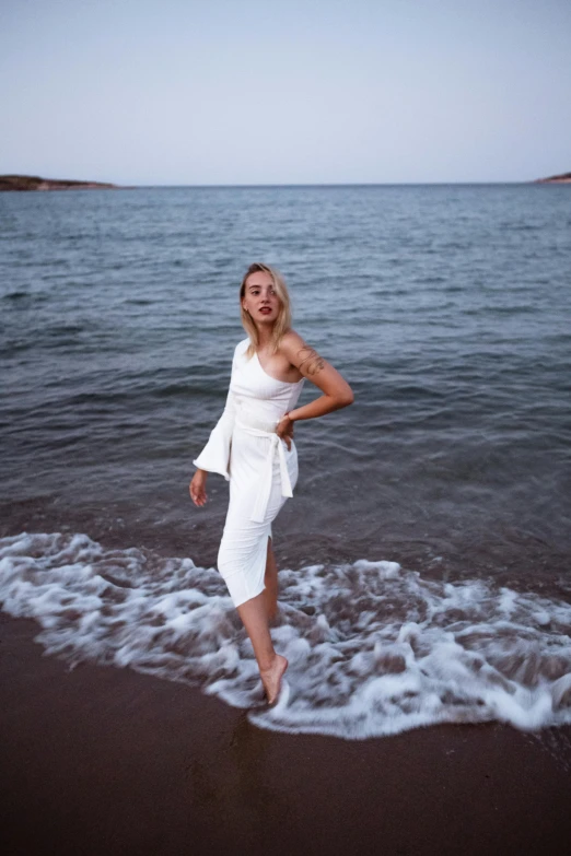 a woman in a white dress standing in the ocean