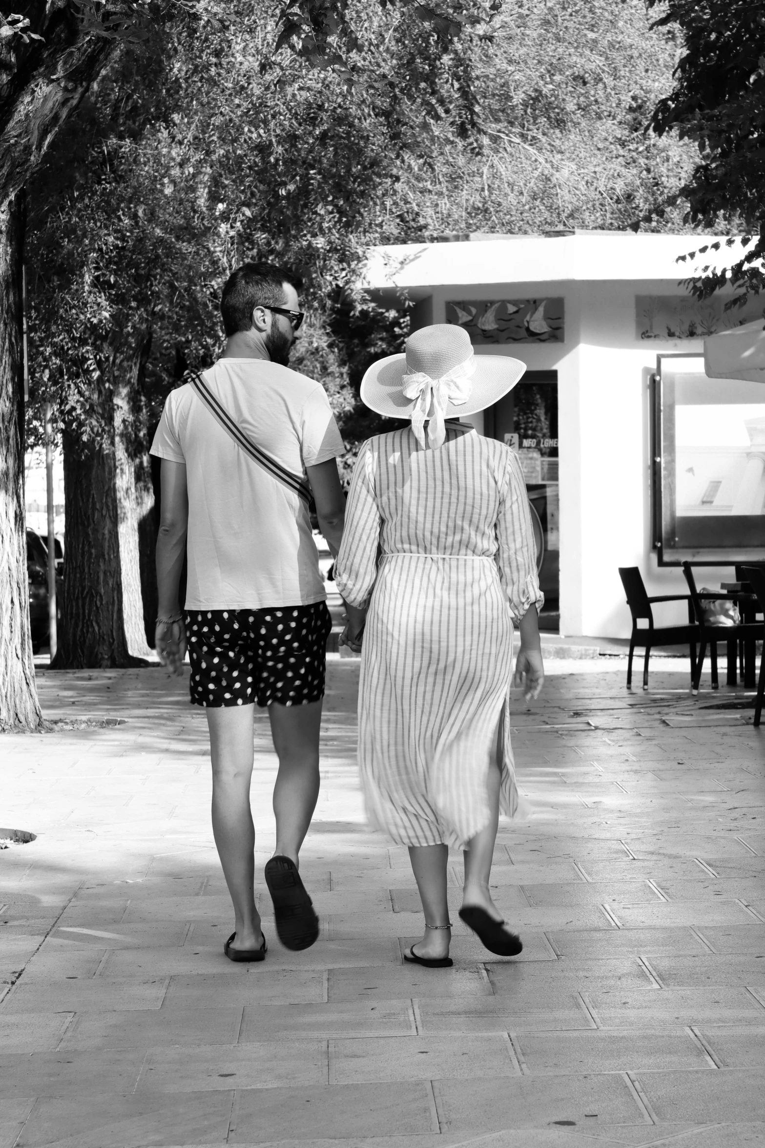 two people walking down the sidewalk holding hands