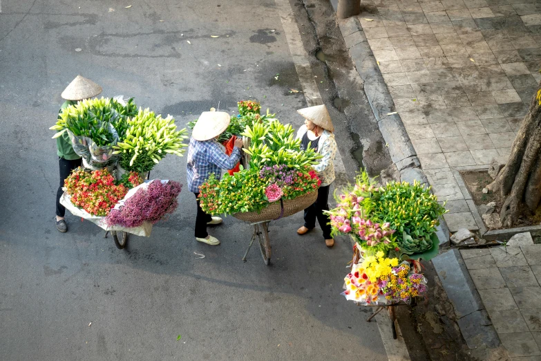 two people carrying baskets of flowers down a city street