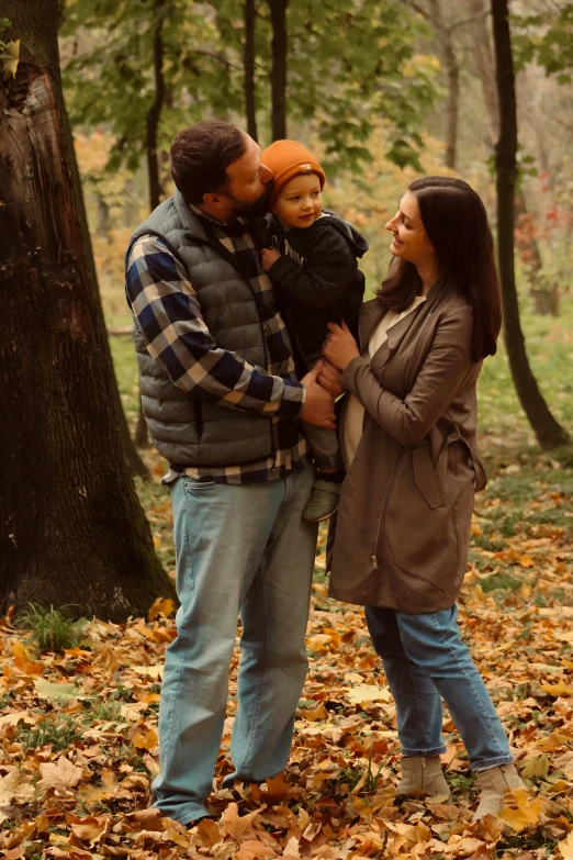 the man is holding the young child and taking pictures in the park