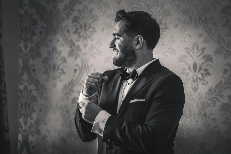 black and white image of a man in a tux with his hands clasped and his face slightly to the side