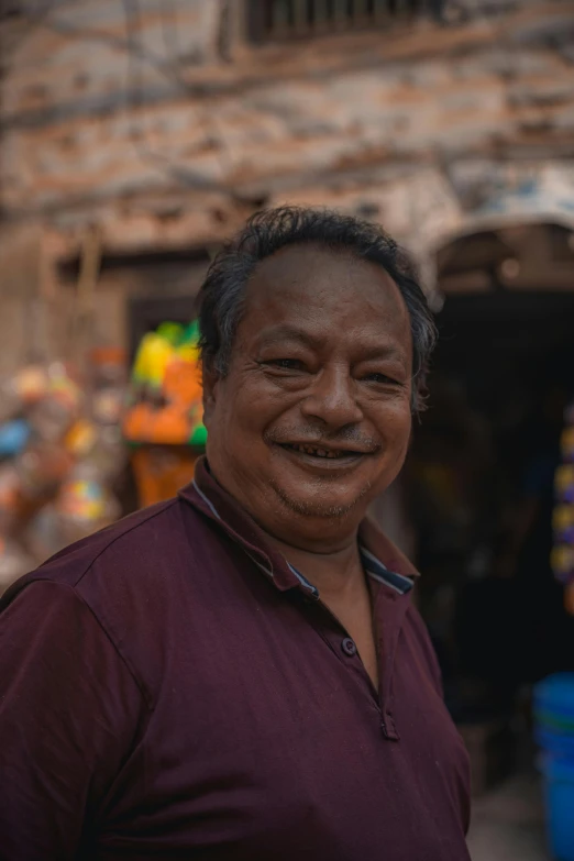 a man smiles into the camera in front of a market