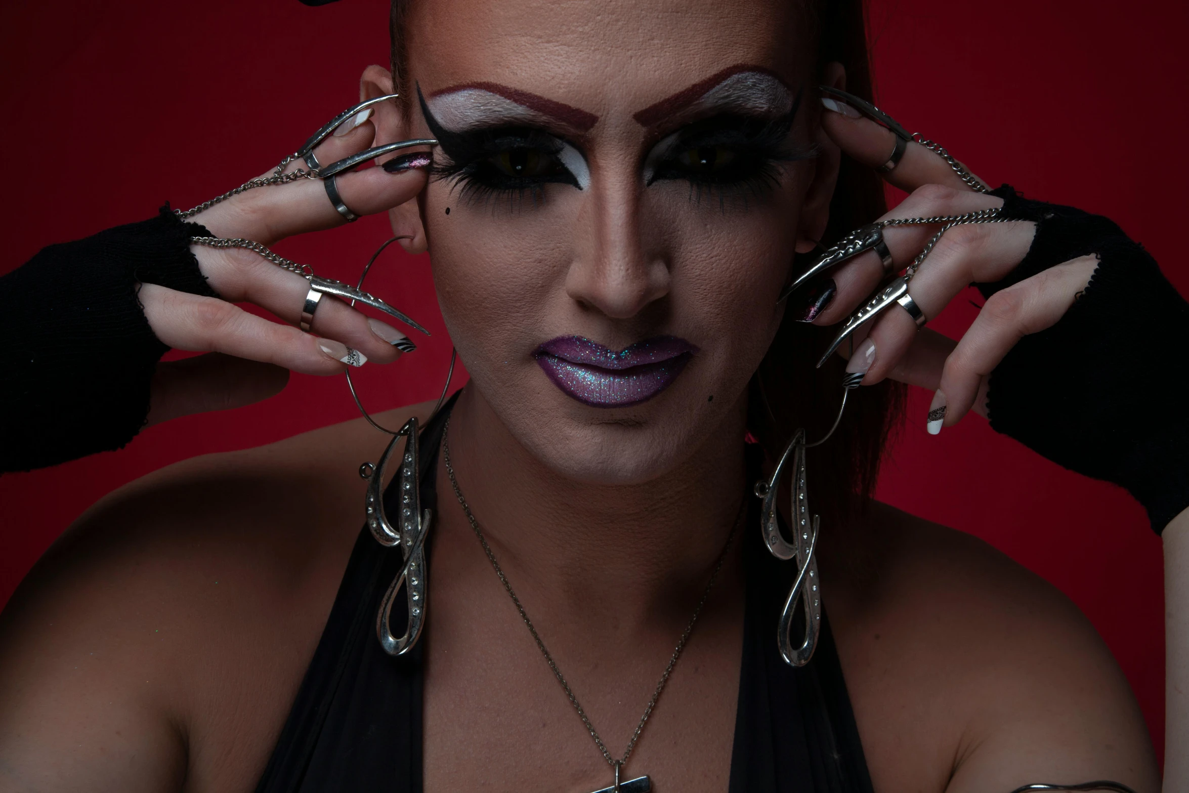 woman with makeup and face art wearing black gloves