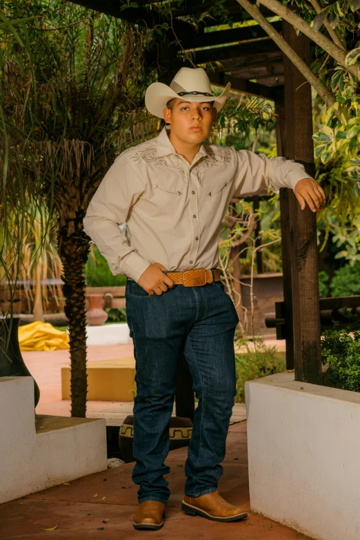 a man standing in cowboy gear by some palm trees