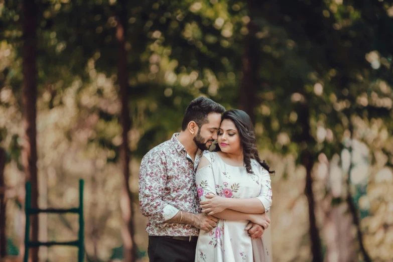 an engaged couple kissing in the middle of a forest