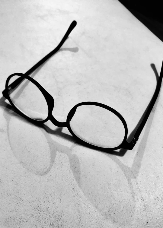 a pair of reading glasses laying on a white surface