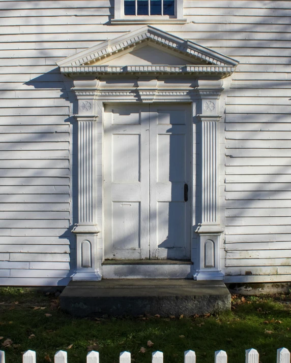 an old white building that has a door and window