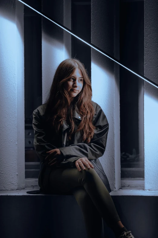 a beautiful young lady sitting on top of a step in front of a wall