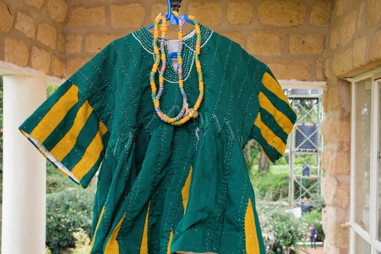 a green and yellow blouse hanging from a stone wall