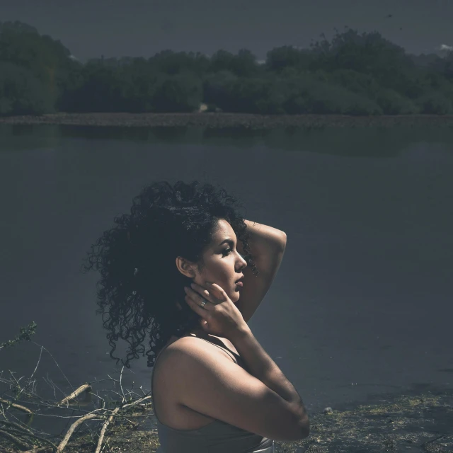 a woman is sitting on the rocks near the water