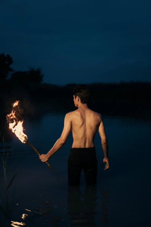 a man holding up a stick in water with fire