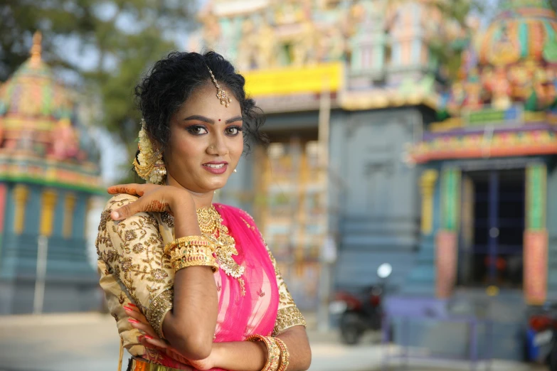 a beautiful woman in a yellow and pink saree standing by some temples