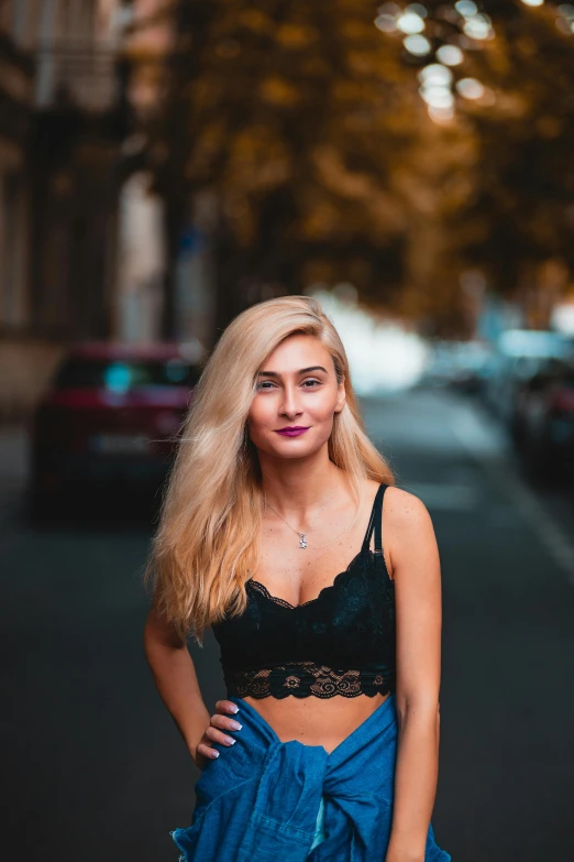 a beautiful blonde haired woman in a top is standing by the road