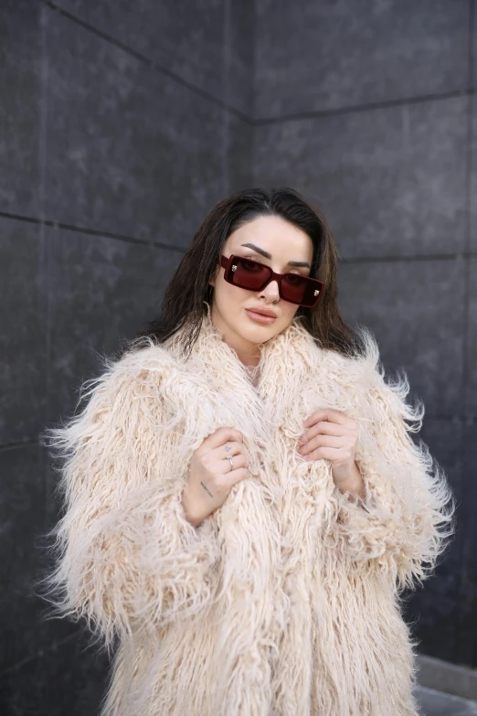 a woman with a furry white coat, sunglasses and a pair of sun glasses