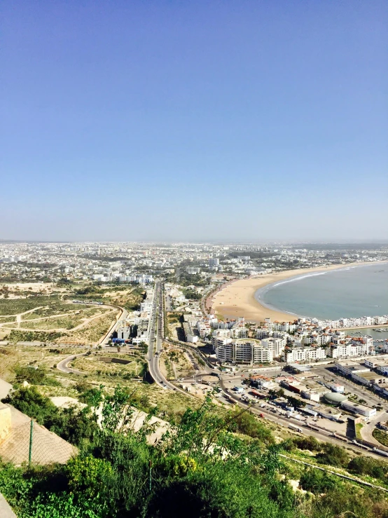 a view of a city and beach from the top of a hill