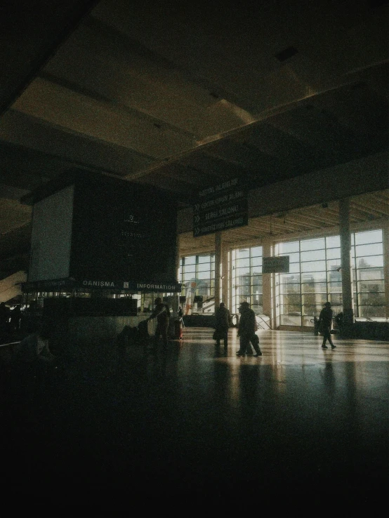 people walking through the lobby near some very big windows