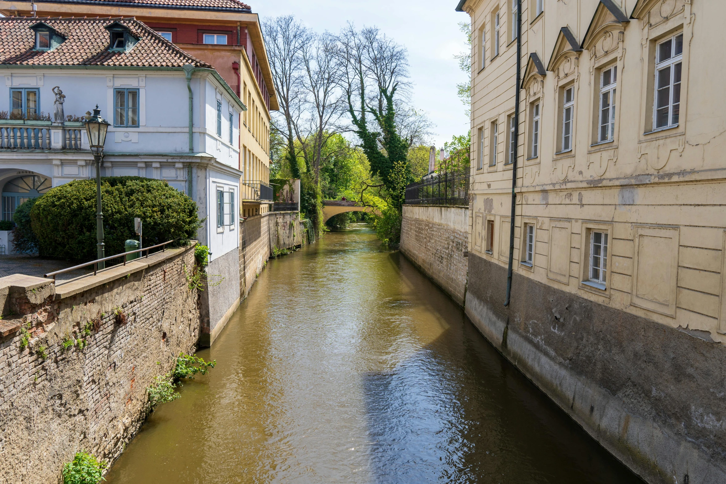 small river running between buildings near buildings on side of street