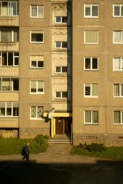 a large brown building with windows near a man on a motorcycle