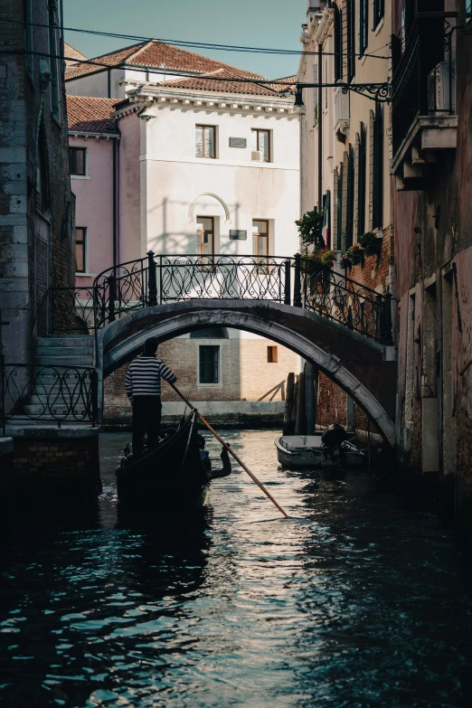 a boat rides through an empty canal with buildings and overhead bridge