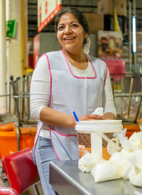 a woman smiling while holding a cup full of clumps of food