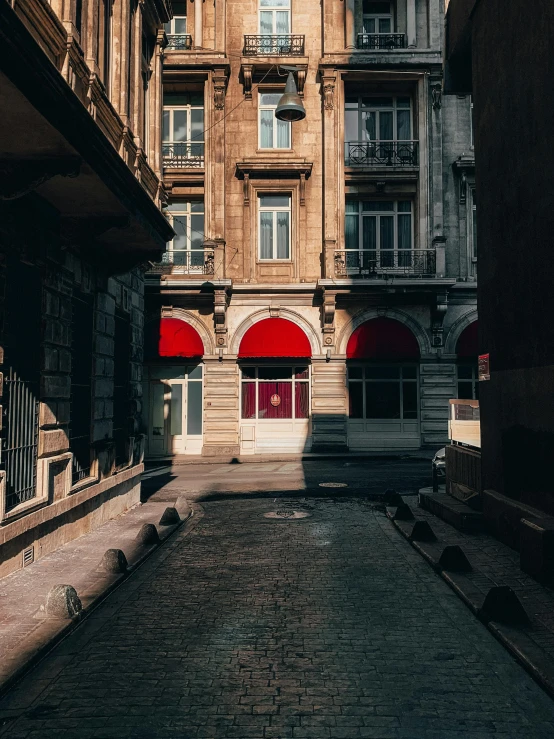 an alley between buildings with closed balconies and brick walkway