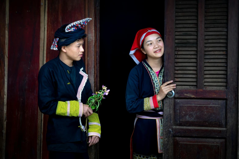 two s wearing headdreses stand next to a doorway