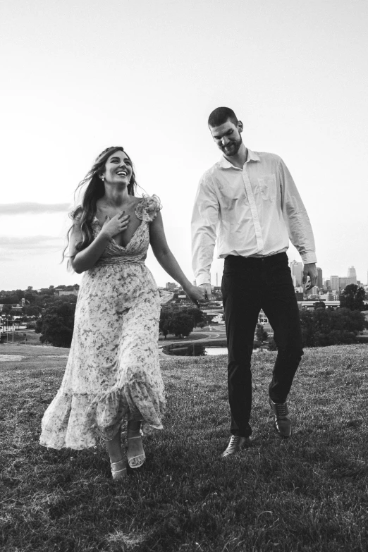 the couple are smiling and walking in a field