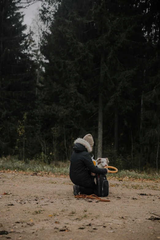 a person with a stuffed animal sits on the ground in a wooded area