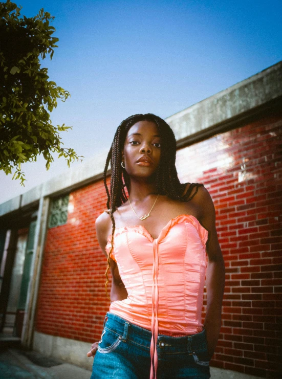 a beautiful young woman in pink top standing by building