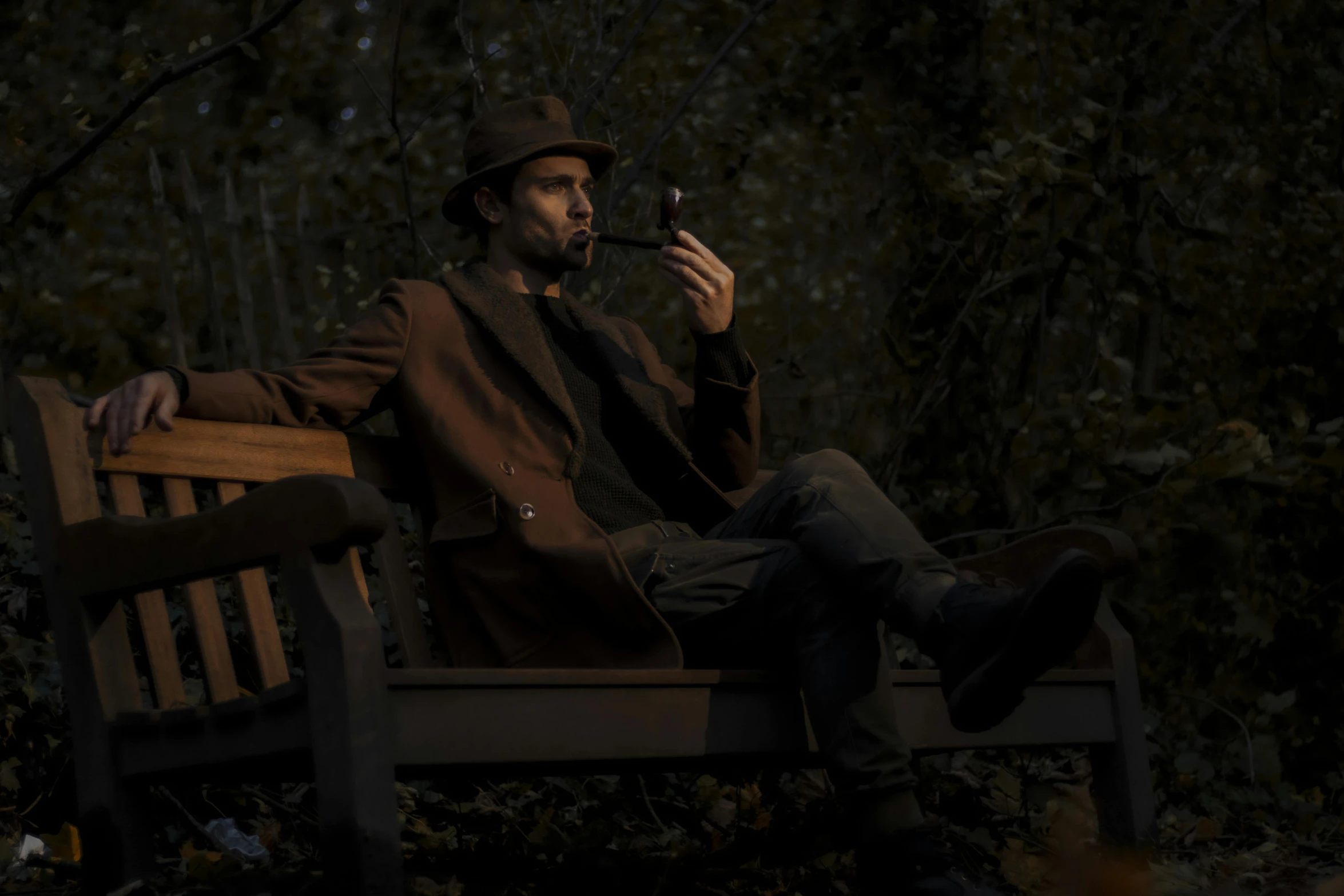 a man in black jacket and hat sitting on wooden bench with a pipe